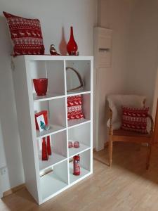 a white book shelf with red vases on it at Ferienwohnung am Steinwald in Krummennaab