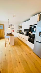 a kitchen with white cabinets and a wooden floor at Tregenna House - St Ives, A Beautiful Newly Refurbished 4 Bedroom Family Town House With Alfresco Dining Garden and Private Parking Spaces in St Ives