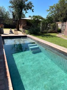 una piscina con agua azul y 2 sillas. en Tanah Host - Casa de Huespedes en Villa Mercedes