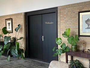 una puerta negra de garaje en una pared de ladrillo con plantas en Atalanta-Wellness Roermond 'de Wethouder' en Herten