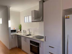 una cucina bianca con lavandino e frigorifero di Smart Modern Close City/Airport WIFI/Park/Netflix a Perth