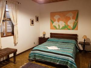 a bedroom with a bed and a painting on the wall at Pousada Madalena in Santa Maria Madalena