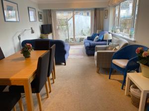 sala de estar con muebles azules, mesa y sillas en Lovely 3 bed ground floor flat with garden, close to the beach, dog friendly, en Seaview