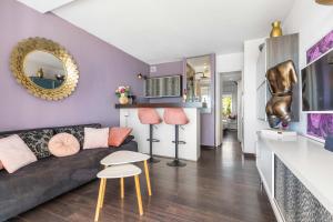 un soggiorno con pareti viola, divano e sgabello. di La vie en rose naturiste - Port Nature a Cap d'Agde