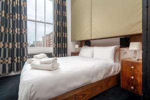 een slaapkamer met een groot bed en handdoeken bij Award-winning designer apartment in Londen