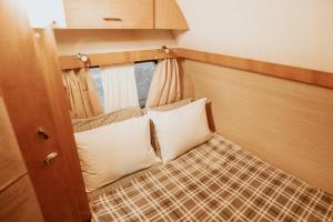 a small bed in a room with a window at La Brume Trailers in Campos do Jordão