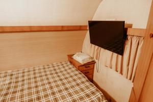 Habitación pequeña con cama y TV. en La Brume Trailers, en Campos do Jordão