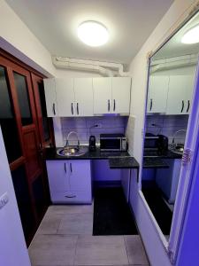 a small kitchen with white cabinets and a sink at Camera/garsoniera in regim hotelier in Comăneşti