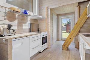 uma cozinha com armários brancos e uma escada numa casa em Hyggeligt og lyst feriehus nær stranden i Klint em Nykobing Sjaelland