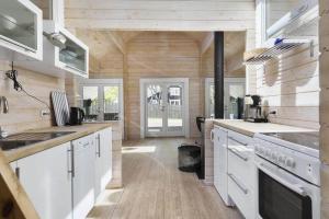 uma cozinha com electrodomésticos brancos e paredes de madeira em Hyggeligt og lyst feriehus nær stranden i Klint em Nykobing Sjaelland