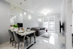 a dining room and living room with a table and chairs at Unique Baltic Apartments - Apartament z garażem in Kołobrzeg