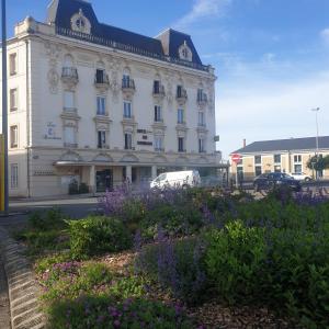 un grand bâtiment blanc avec des fleurs devant lui dans l'établissement Logis Hotel des Bourbons, à Montluçon