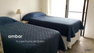 2 camas con edredones azules en un dormitorio en Casa Ambar, vista al mar, Punta del Diablo,Uruguay, en Punta del Diablo