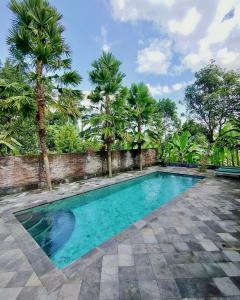 a swimming pool in a yard with palm trees at Alas Arum Ecolodge in Tabanan