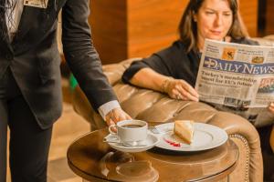 a woman with a cup of coffee and a piece of cake at Kahya Hotel Ankara in Ankara