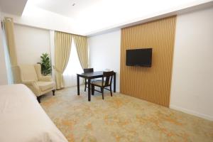 a hotel room with a desk and a television on a wall at OMAR BB STUDIO in Kota Bharu