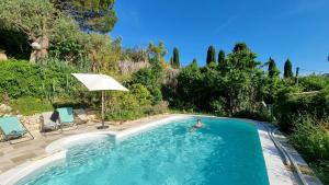 uma pessoa numa piscina com um guarda-chuva em La Maison De La Cadière em La Cadière-dʼAzur