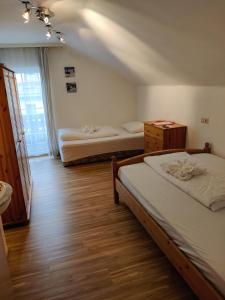 2 łóżka w pokoju z drewnianą podłogą w obiekcie Pension Reiterhaus w mieście Wagrain