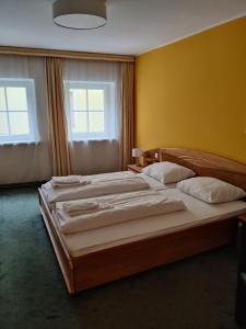 two beds in a room with yellow walls and two windows at Pension Reiterhaus in Wagrain