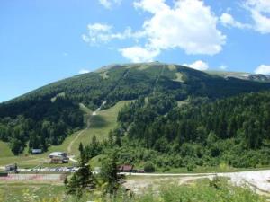 a green mountain with a road on it at Panorama View apartman in Bjelašnica
