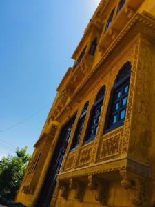 ein gelbes Gebäude mit Seitenfenstern in der Unterkunft Vamoose Thakurji Palace in Jaisalmer
