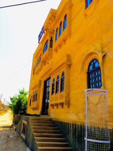ein gelbes Gebäude mit einer Treppe davor in der Unterkunft Vamoose Thakurji Palace in Jaisalmer