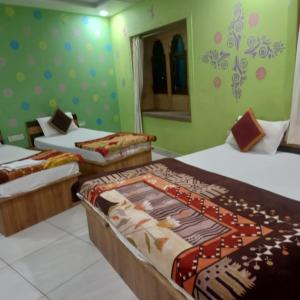 3 Betten in einem Zimmer mit grünen Wänden in der Unterkunft Vamoose Thakurji Palace in Jaisalmer