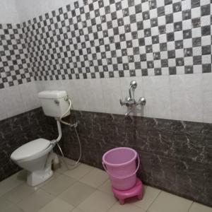 a bathroom with a toilet and a pink bucket at Vamoose Thakurji Palace in Jaisalmer