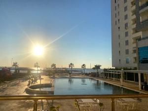 a view of a swimming pool with the sun in the sky at Durrës BelleVue 3 bdm Apartment in Durrës