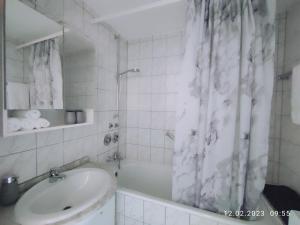 La salle de bains est pourvue d'un lavabo et d'un rideau de douche. dans l'établissement Apartment Waldblick - 77 qm, 2 Schlafzimmer, Balkon und Wi-Fi, à Maulburg
