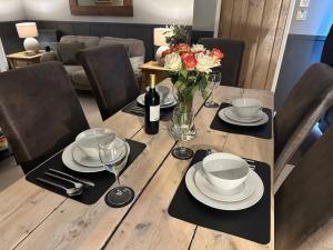 uma mesa de madeira com pratos e um vaso de flores em Meadow Cottage em Salisbury