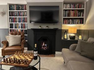uma sala de estar com um tabuleiro de xadrez e uma lareira em Meadow Cottage em Salisbury