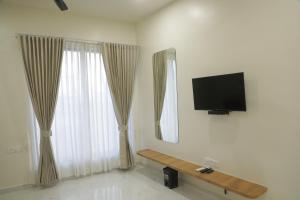 uma sala de estar com televisão e duas janelas em Hotel Panch em Kalol