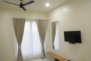uma sala de estar com uma televisão de ecrã plano e cortinas em Hotel Panch em Kalol