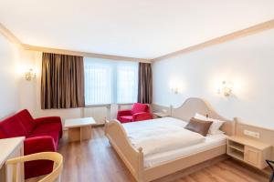 a hotel room with a bed and two red chairs at Hotel Eisensteiner Hof in Bayerisch Eisenstein