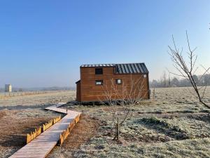 a wooden house in a field with a wooden walkway at Tiny House 