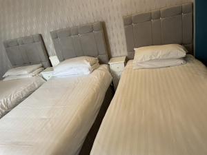 three beds in a room with white sheets and pillows at Diamonds Inn in York