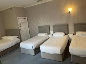 a room with three beds with white sheets at Diamonds Inn Ltd in York