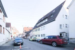 uma rua com carros estacionados ao lado de um edifício branco em ALFA Stuttgart 3Zi-Maisonette 6 Personen Zuffenhausen nahe Porsche & Bosch l WIFI & SmartTV I 3BR 4 Beds I Kitchen I Bathroom & WC em Estugarda