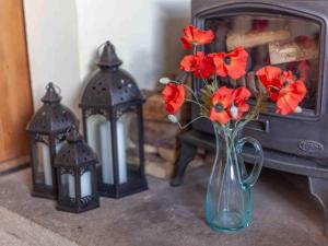 a vase with red flowers in it next to two lights at Shaftoe's Bed and Breakfast in Haydon Bridge