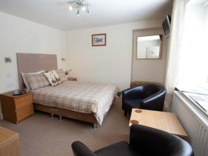 um quarto com uma cama, uma secretária e cadeiras em Shaftoe's Bed and Breakfast em Haydon Bridge