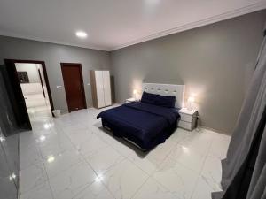 ein Schlafzimmer mit einem blauen Bett und einem weißen Fliesenboden in der Unterkunft شالهيات درة العروس in Durrat Al-Arus