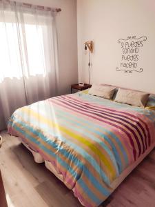 a bed with a colorful blanket on it in a bedroom at Mi casa es tu casa - PC Home in El Calafate