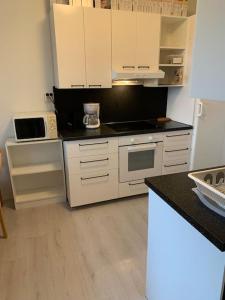 a kitchen with white cabinets and a black counter top at Tonnila, big villa for 10-Person at Turku near Meyer gate in Turku
