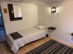 a small bed in a white room with a light at Omakotitalo, Perno (near Meyer gate) in Turku