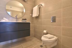 a bathroom with a toilet and a sink and a mirror at Bat-Galim Beach Apartment in Haifa +23 photos