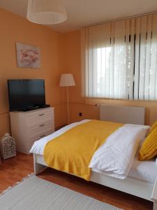 een slaapkamer met een bed met een gele deken en een televisie bij Mónika Vendégház in Mórahalom