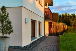 a white building with a tree next to a fence at Nord29 - Exklusive Ferienwohnung am Waldrand Meschede in Meschede