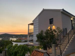 a white house with a sunset in the background at Apartman Vitanov in Vinišće