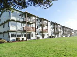 un immeuble d'appartements avec une pelouse devant lui dans l'établissement Canterbury Inn, à Ocean Shores